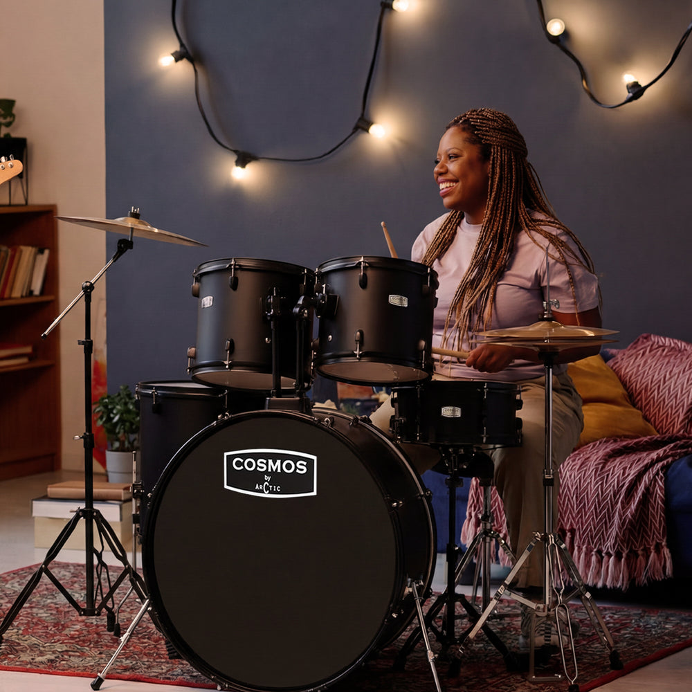 Full studio shot of a 5-piece black acoustic drum set, featuring a glossy black finish with chrome hardware, bass drum, snare, two rack toms, a floor tom, crash cymbal, and hi-hats.