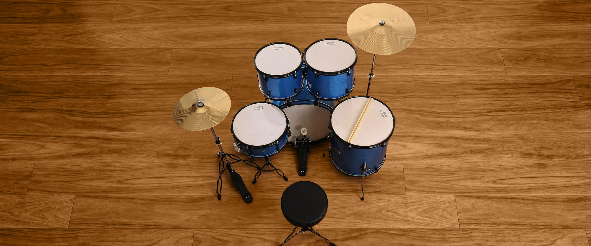 Elevated angle desktop shot of a blue acoustic drum kit, highlighting the polished blue shells, chrome mounting system, and white drumheads.