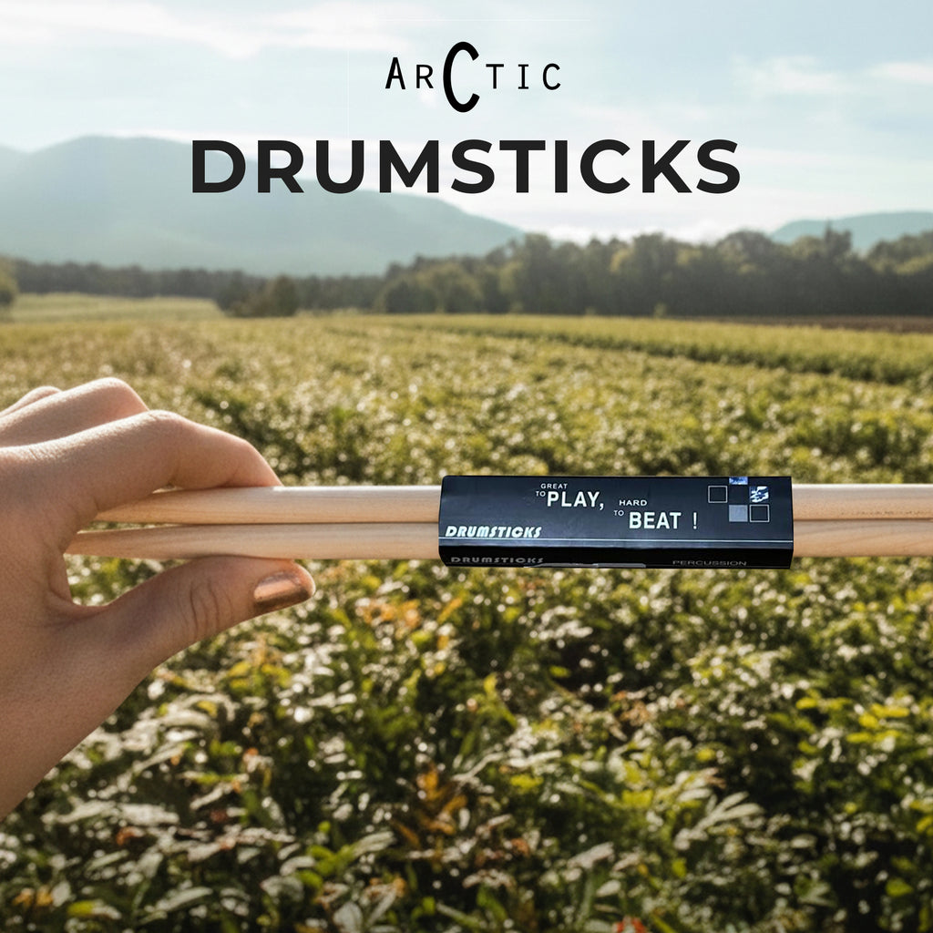 Drumsticks held by a hand with 'Arctic Drumsticks' branding against a scenic background.