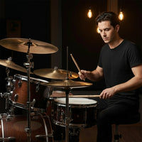 Man playing drums in a dimly lit room with hanging light bulbs.