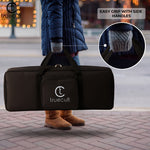Person holding a black bag with 'truecult' branding, featuring side handles. padded 37-key keyboard bag for Yamaha Casio