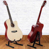 Two acoustic guitars on stands against a white brick wall.